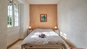 Un dormitorio con una cama, dos lámparas de noche, una ventana y un cuadro en la pared.