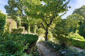Un jardin agrémenté de divers arbres et arbustes, d’un chemin de gravier et d’une clôture en bois.