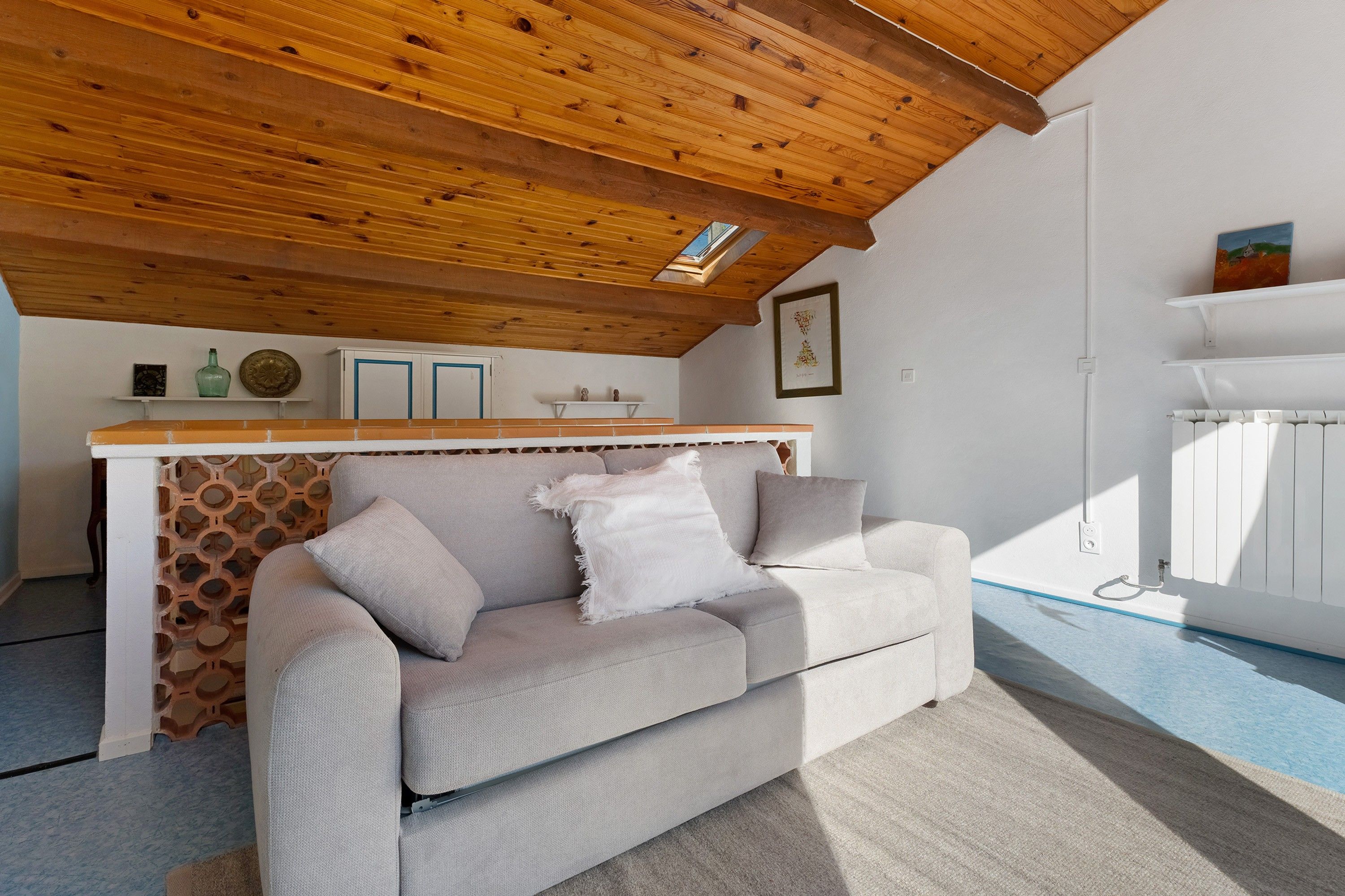 Ein modernes Wohnzimmer mit Holzboden, einer Couch, einer Wand mit Dekoration und einer Heizung.