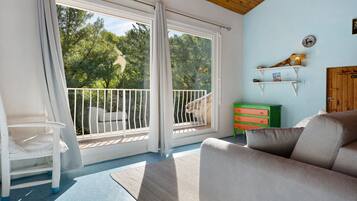 A room with a balcony, a white chair, a sofa, and a green dresser.