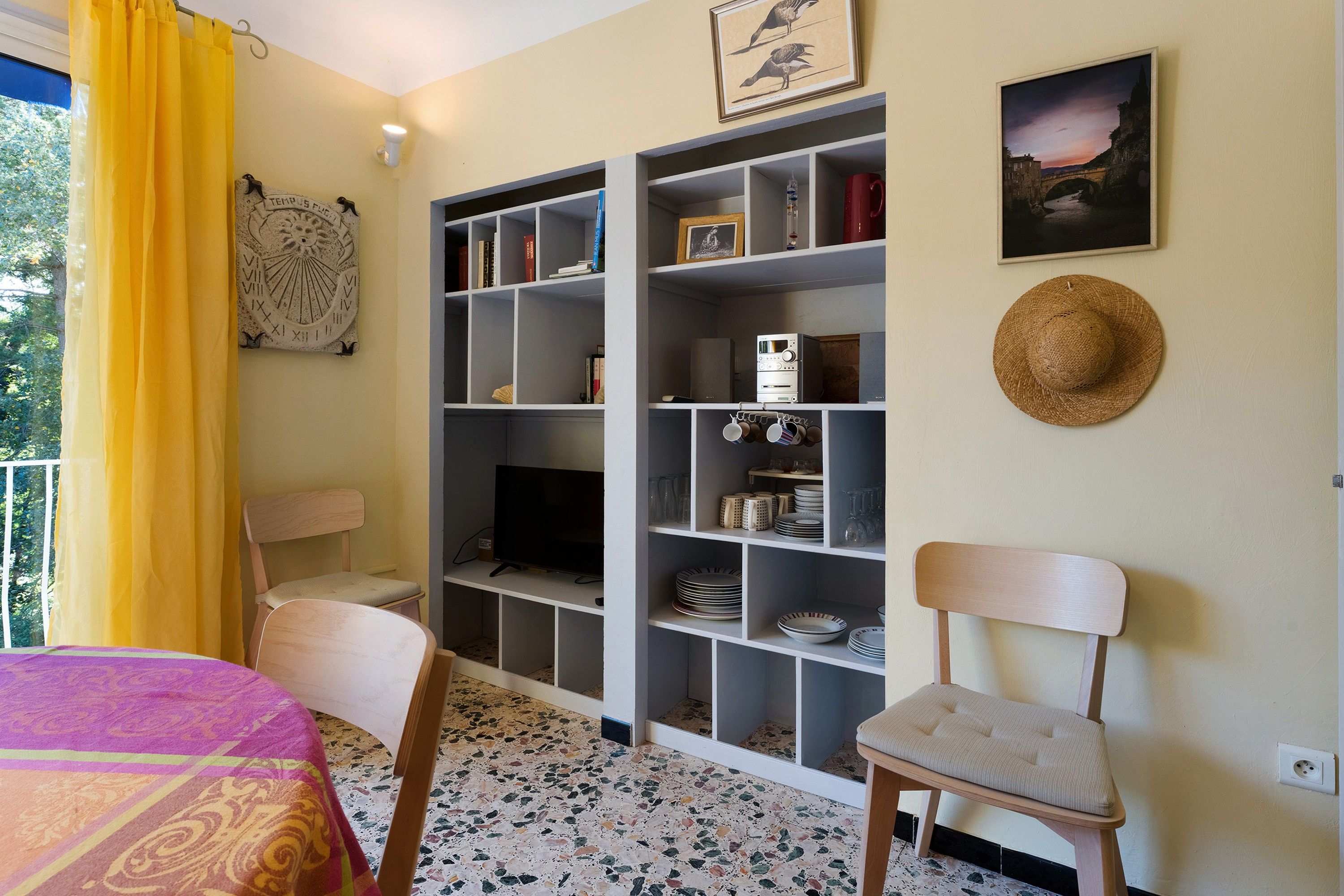 Ein Zimmer mit einem Bett, einem Sessel, einem Bücherregal und einem Fernseher.