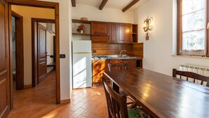 Une cuisine avec des meubles de rangement en bois, un réfrigérateur, un évier et une table à manger avec des chaises.