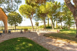 Un espacio al aire libre con mesas y sillas, rodeado de árboles y vistas al campo.