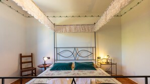 Une chambre à coucher avec un lit, une chaise, une table de chevet et une table avec une lampe.