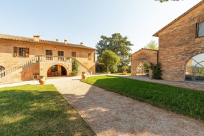 Un patio con un edificio de ladrillo, una escalera de piedra y un árbol grande.