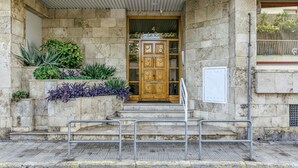 Un bâtiment en pierre avec une porte en bois, des marches et des garde-corps en métal.