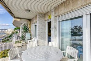 Ein Balkon mit Tisch und Stühlen, einem Blumentopf und Blick auf die Stadt.
