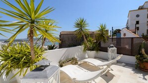 Une terrasse sur le toit, avec un hamac, des plantes en pot et une vue sur la ville.