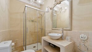 Une salle de bain avec une douche à parois de verre, un lavabo avec un miroir au-dessus et des toilettes.