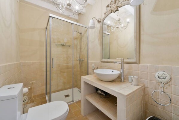 Une salle de bain avec une douche à parois de verre, un lavabo avec un miroir au-dessus et des toilettes.