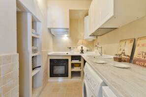 Une cuisine compacte équipée d’un four encastré, d’un lave-linge et d’un évier.