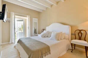 Quarto com cama, cadeira, televisão e porta que dá para o exterior.