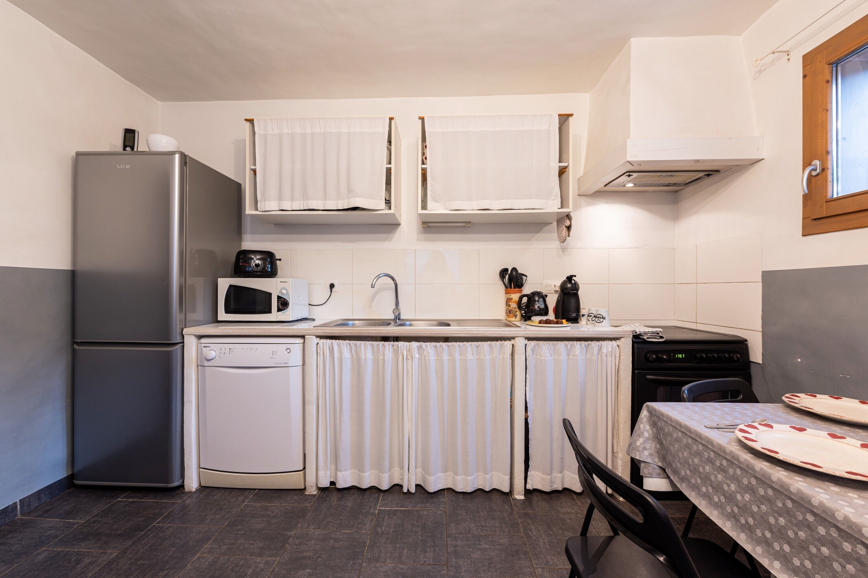 Una cocina compacta equipada con refrigerador, microondas, lavamanos y estufa.