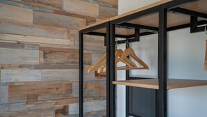 Une pièce avec un lambris en bois et une étagère en métal noir, dotée de supports en bois pour suspendre les vêtements.