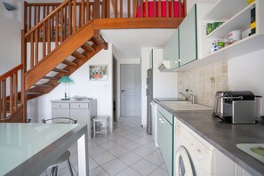 Een keuken met een wasmachine, een broodrooster en een houten trap.