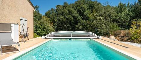A swimming pool with a sunshade, a lounge chair, and exercise equipment.