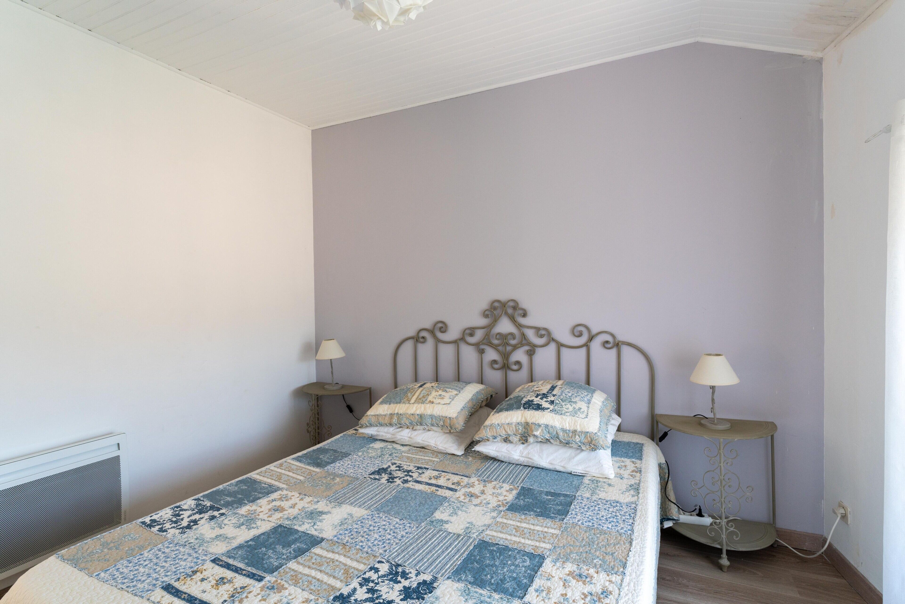 A bedroom with a bed, two bedside tables, a lamp on each table, and a radiator.