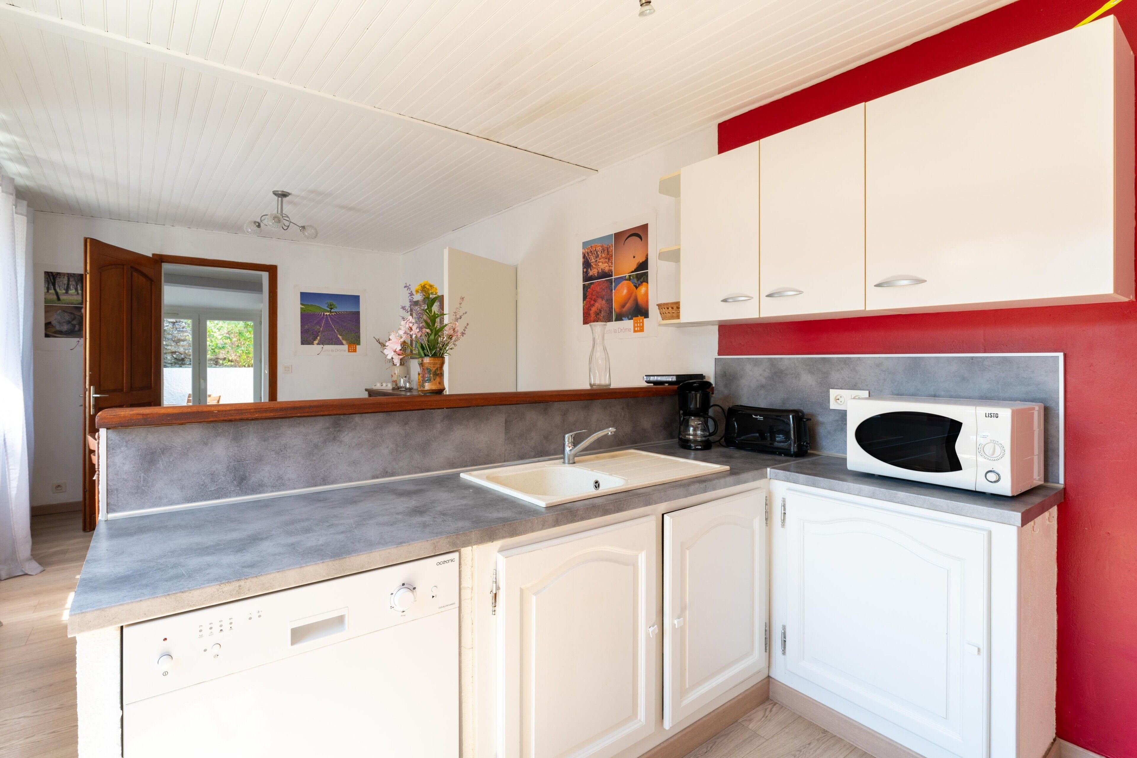 A kitchen with a grey countertop, white cabinets, a microwave, and a coffee maker.