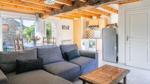 Un salon chaleureux avec un canapé, une table basse en bois et une cuisine en arrière-plan.