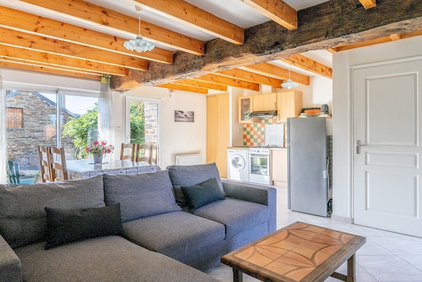 Una sala de estar acogedora con un sofá, una mesa de centro de madera y una cocina al fondo.