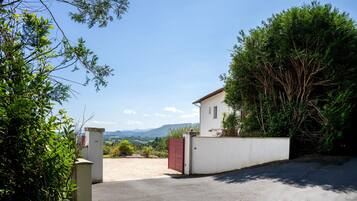 A gated property with a white building, a paved driveway, and a view of mountains.