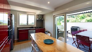 Una cocina moderna con una mesa de madera, armarios rojos y vista a zonas verdes.