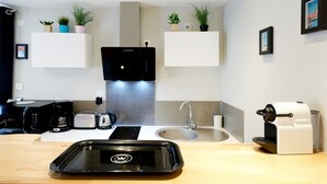 A modern kitchen with a coffee machine, toaster, and sink. - Holiday Apartment "Escapade Au Pays Basque 2 to 4 Guests" with Balcony, Shared Garden & Wi-Fi (Urrugne)