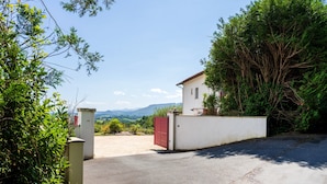 A gated property with a white building, a red gate, and a view of mountains. - Holiday Apartment "Escapade Au Pays Basque 2 to 4 Guests" with Balcony, Shared Garden & Wi-Fi (Urrugne)