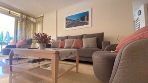 A living room with a sofa, a coffee table, and a potted plant. - Apartment 'Apartamento Cal Albir' with Shared Pool, Wi-Fi and Air Conditioning (l'Alfàs del Pi)
