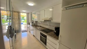 A modern kitchen with white cabinets, a built-in oven, a microwave, and a coffee maker. - Apartment 'Apartamento Cal Albir' with Shared Pool, Wi-Fi and Air Conditioning (l'Alfàs del Pi)
