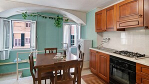 A kitchen with wooden cabinets, a gas stove, a washing machine, and a dining table with chairs.