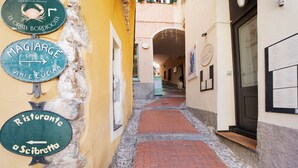 A narrow alleyway with signs for 'La Cucuta Bordigotti,' 'Magiarge,' and 'Ristorante a Scibrette.'