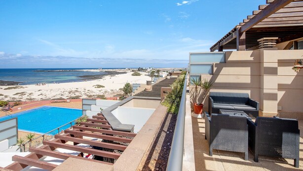 A pool, outdoor seating, and a beach view.
