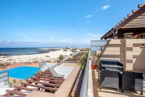 A pool, outdoor seating, and a beach view.