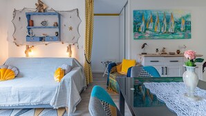 A room with a bed, a desk, a chair, a painting, and a small table with a vase. - Studio Apartment 'Cabine Centre Ville' with Wi-Fi (ARCACHON)
