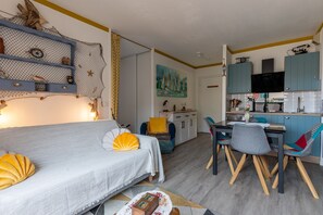 Un salon confortable avec un canapé, une table à manger et un coin cuisine équipé de placards et d’un téléviseur.