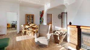Un vaste salon doté d’une cheminée, un coin repas avec des meubles en bois et un grand tableau accroché au mur.