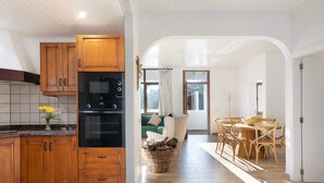 Une cuisine avec des meubles en bois, un four noir et un coin repas comprenant une table et des chaises.