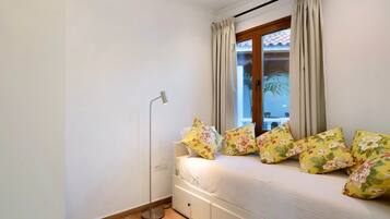 Een slaapkamer met een bed, een vloerlamp en een raam met gordijnen.