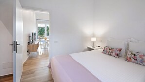Un dormitorio con una cama, una mesita de noche, una lámpara y vista a un comedor.