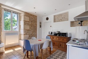 Una cocina compacta con pared de piedra, una zona de comedor con mesa y sillas, y un horno empotrado.