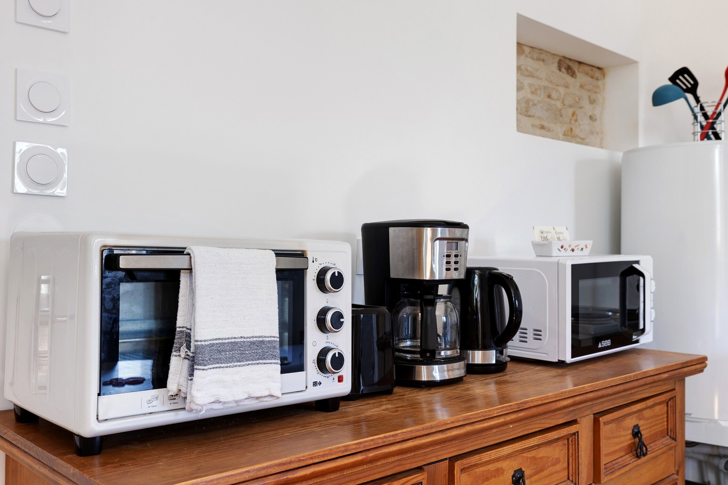 Een kitchenette met een broodrooster, koffiezetapparaat en magnetron op een houten aanrecht.