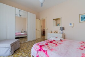 Ein Schlafzimmer mit Bett, Kleiderschrank, Spiegel, Nachttisch und Lampe.