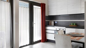 Una cocina con diseño moderno, que incluye una estufa, armarios y un comedor con mesa y sillas.