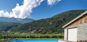 A swimming pool with a mountain view, a wooden building, and a stone wall. - Studio apartment 'Agriturismo L'isola Del Cavallo 3' with Mountain View, Shared Garden and Wi-Fi (Talamona)