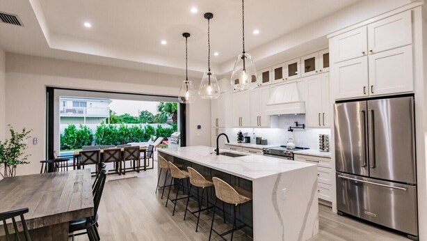 Una cocina moderna con una isla grande, electrodomésticos de acero inoxidable y vistas al exterior.
