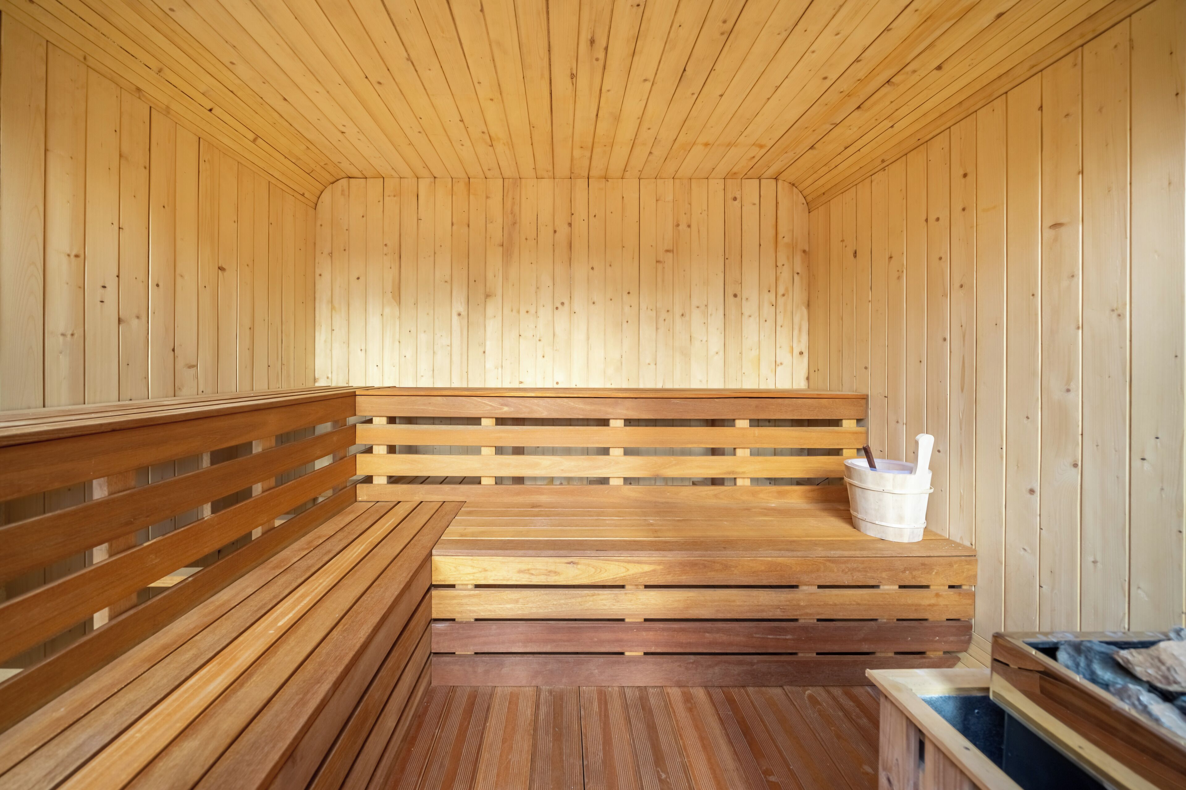 A wooden sauna with benches and a bucket.