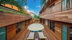 A wooden deck with a table and chairs under a white umbrella, surrounded by wooden walls and large windows. - ZenDen (Tibubeneng)