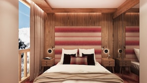 Une chambre à coucher avec une tête de lit en bois, un lit recouvert de draps blancs, deux tables de chevet avec des lampes et une vue sur des montagnes enneigées par la fenêtre.