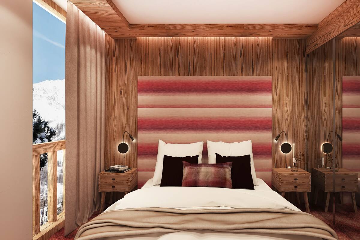 Ein Schlafzimmer mit hölzernem Kopfteil, einem Bett mit weißer Bettwäsche, zwei Nachttischen mit Lampen und Blick auf verschneite Berge durch ein Fenster.